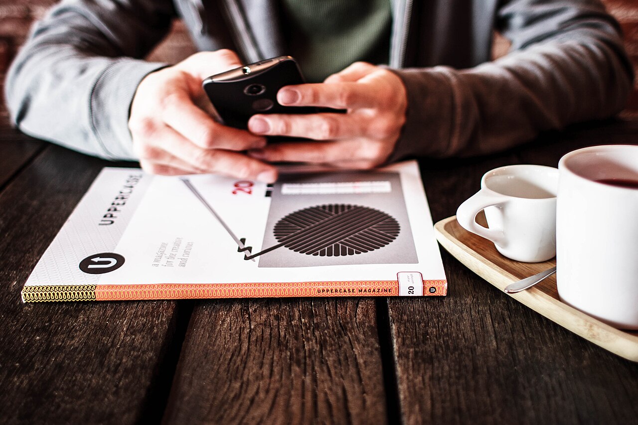 A smartphone beside a cup of coffee